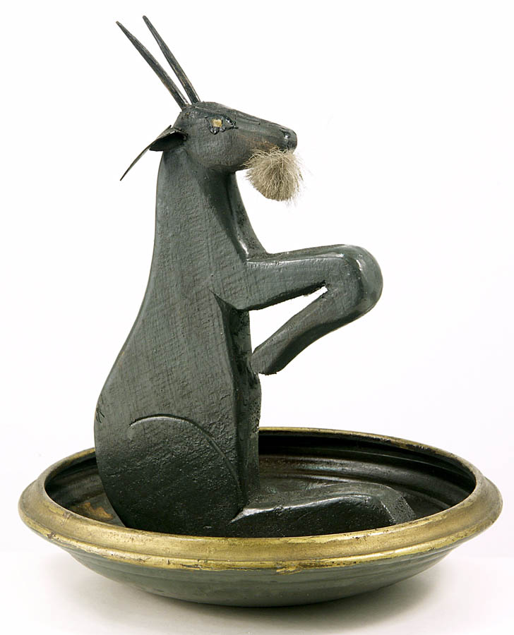 Fotografia w kolorze przedstawiająca wyrzeźbioną z drewna figurkę przypominającego czarnego kozła.